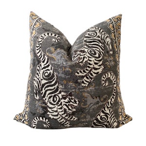 May include: A gray throw pillow with a white and black tiger print. The pillow has a gold and brown border.