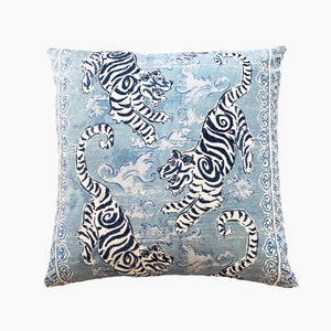 May include: A blue and white throw pillow with a repeating pattern of tigers and clouds. The pillow has a decorative border.