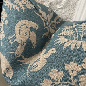 May include: Teal blue fabric with a white and beige floral pattern. The pattern features birds and leaves.