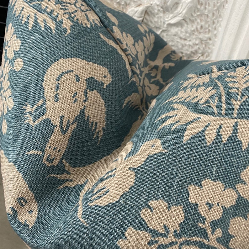 May include: Teal blue fabric with a white and beige floral pattern. The pattern features birds and leaves.