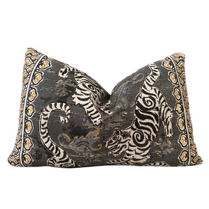 May include: A decorative pillow with a gray background and a black and white tiger print. The pillow has a gold and white border.