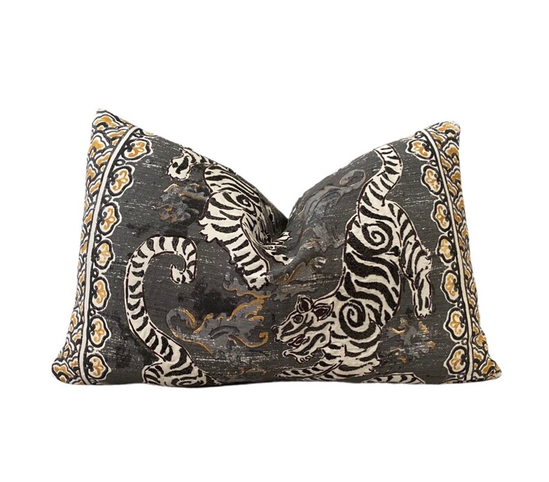 May include: A decorative pillow with a gray background and a black and white tiger print. The pillow has a gold and white border.