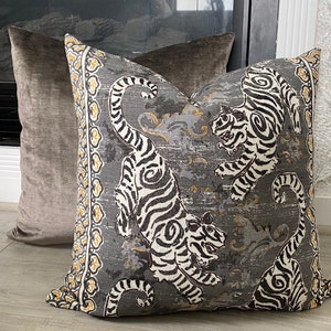 May include: A gray and white patterned throw pillow with a design of tigers. The pillow has a yellow and black border.