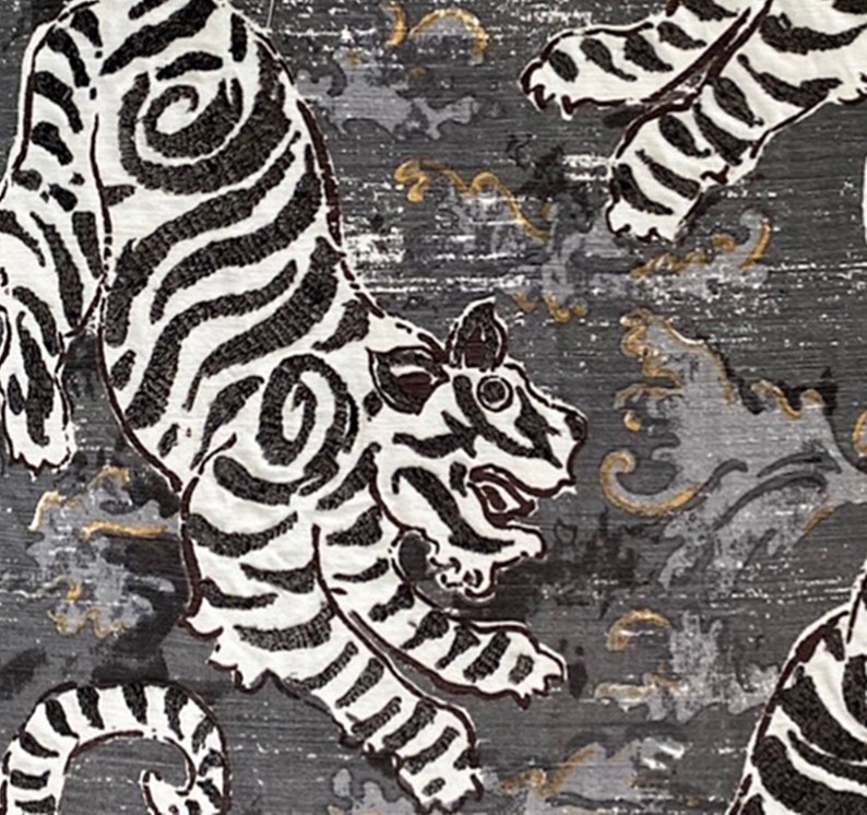 May include: A black and white patterned fabric with a repeating design of tigers. The tigers are stylized and have a traditional Japanese look. The background is a dark gray with gold accents.
