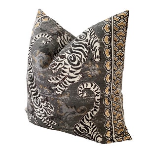 May include: A gray pillow with a black and white tiger print and a gold and brown border.