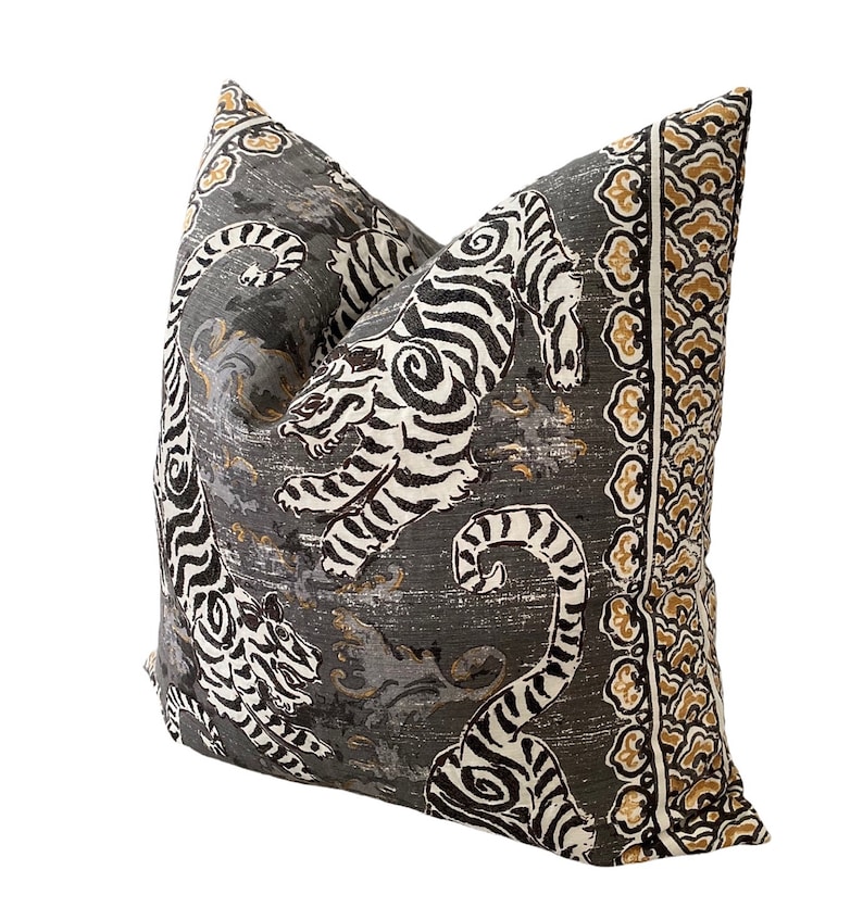 May include: A gray pillow with a black and white tiger print and a gold and brown border.
