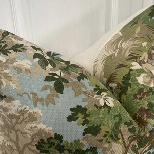 May include: Two throw pillows with a floral pattern featuring green leaves, brown branches, and white flowers on a light blue background.