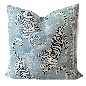 May include: A blue and white throw pillow with a repeating pattern of tigers and clouds. The pillow has a decorative border.