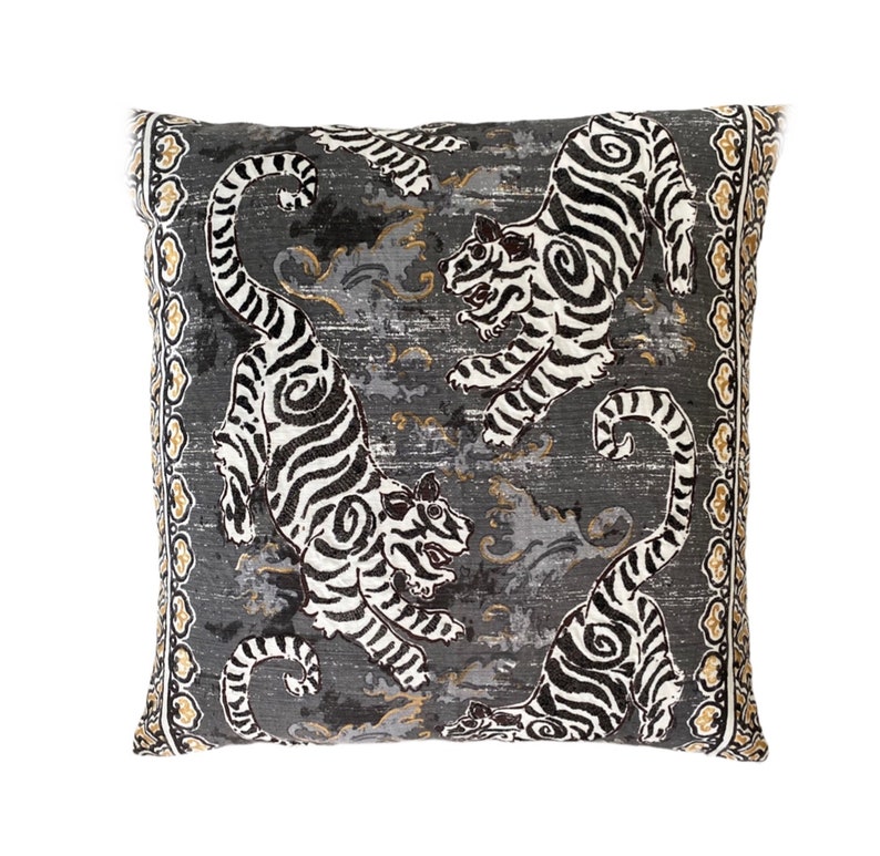 May include: A gray and white decorative pillow with a repeating pattern of black and white tigers on a gray background. The pillow has a gold and white border.