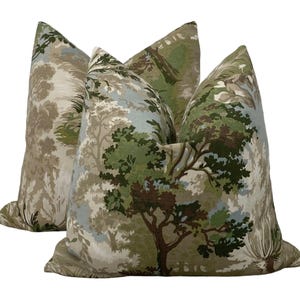 May include: Two decorative throw pillows with a green, brown, and blue forest print. The pillows are made of a soft, textured fabric.