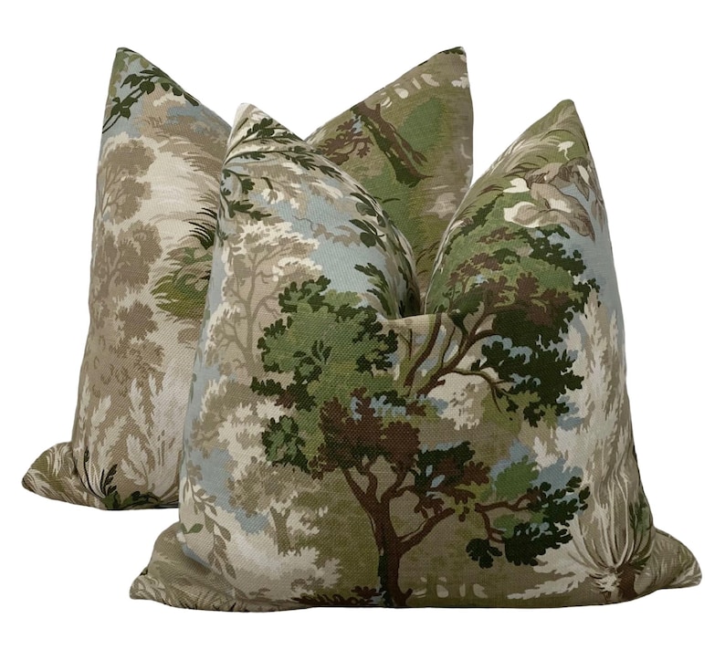 May include: Two decorative throw pillows with a green, brown, and blue forest print. The pillows are made of a soft, textured fabric.