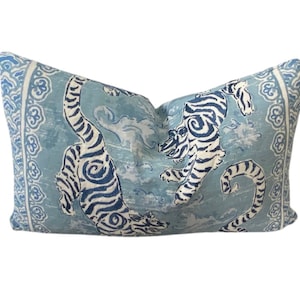 May include: A blue and white pillow with a design of two tigers in a swirling pattern. The pillow has a light blue background with white and blue details.