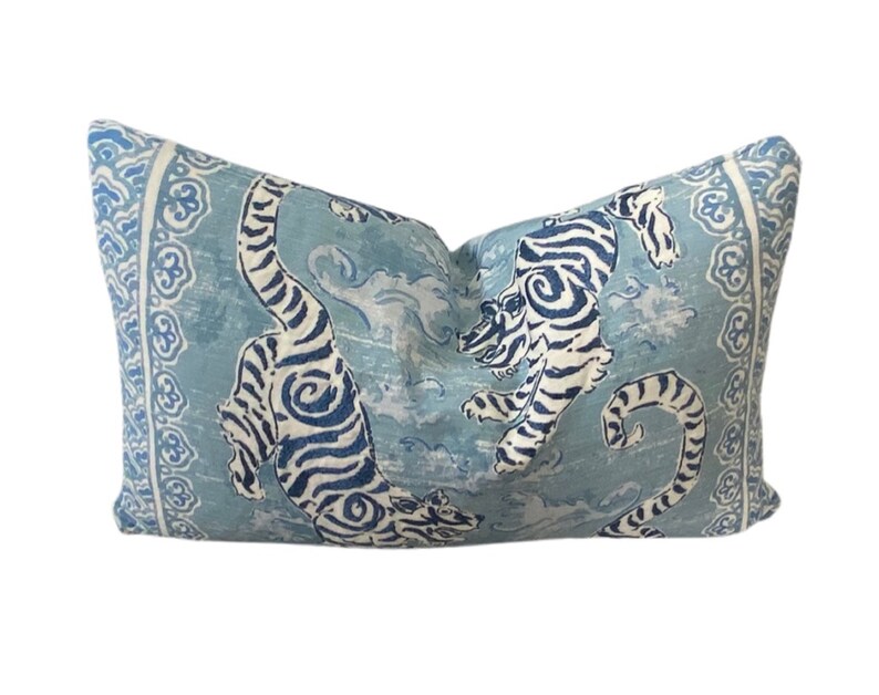 May include: A blue and white pillow with a design of two tigers in a swirling pattern. The pillow has a light blue background with white and blue details.