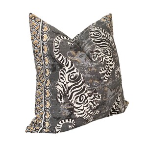May include: A gray pillow with a white and black tiger print. The pillow has a gold and white border with a floral pattern.