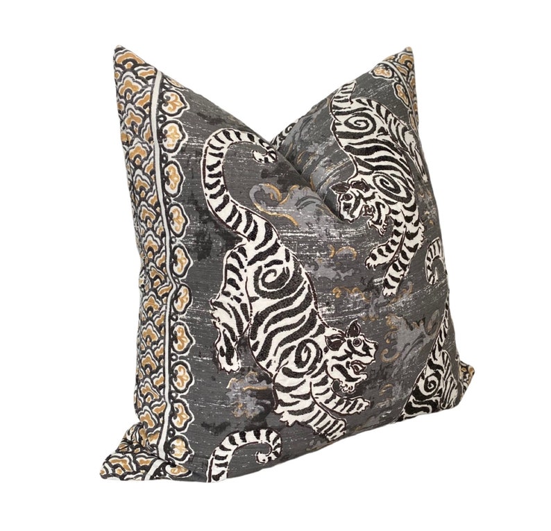 May include: A gray pillow with a white and black tiger print. The pillow has a gold and white border with a floral pattern.