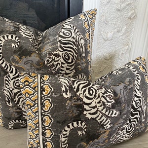 May include: Two decorative throw pillows with a gray background and a white and black tiger print. The pillows have a gold and white border with a floral design.