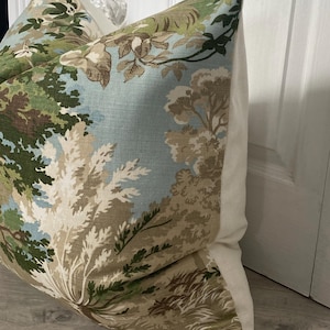 May include: A blue and green patterned pillow with a white border. The pattern features a woodland scene with trees and foliage.