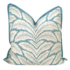 May include: A teal blue throw pillow with a white leaf pattern. The pillow has a teal blue border.