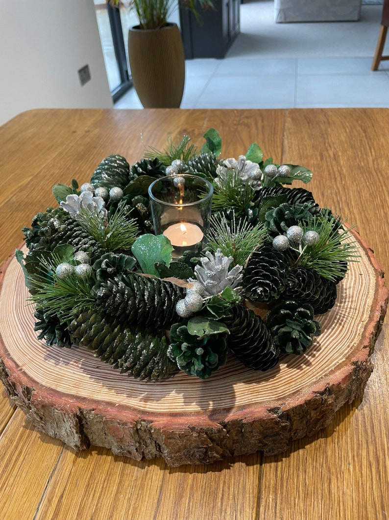 Christmas table centrepiece decoration with a real log slice stand, green foliage and dried cones, sparkly silver cones and baubles image 1