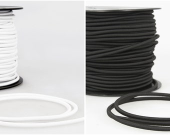 May include: Two spools of elastic cord, one white and one black. The cord is wound around the spools and there is a length of cord lying next to each spool.