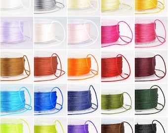 May include: Assortment of 18 spools of waxed cotton cord in various colours, including purple, green, blue, red, orange, brown, black, white, and yellow. Each spool is wound with a length of cord.