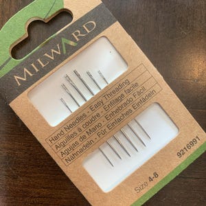 May include: A packet of Milward hand needles for easy threading. The needles are size 4-8 and come in a pack of six. The packaging is brown and green with text in multiple languages.