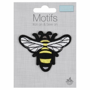 May include: Iron-on or sew-on bee patch with black and yellow stripes, white wings, and a grey head. The patch is on a grey background with the text "Motifs Iron on & Sew on" and "Trimits*" printed on the card.