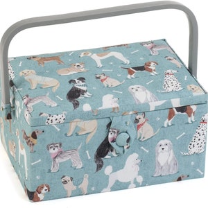Peut inclure: Une boîte à couture en tissu bleu avec une poignée grise. La boîte est décorée d'un motif de chiens de différentes races et poses. La boîte a une fermeture à bouton.