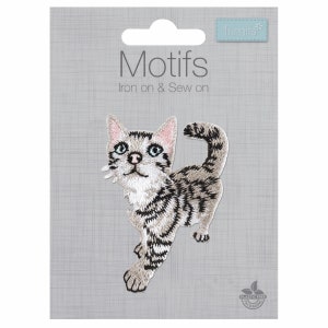 Könnte beinhalten: Ein gestickter Bügel- oder Näh-Aufnäher mit einem grau-weißen Tabby-Kätzchen mit blauen Augen. Der Aufnäher befindet sich auf einem grauen Hintergrund mit dem Text "Motifs Iron on & Sew on" und einem kleinen Logo mit der Aufschrift "Trimits".