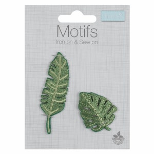 May include: Two green embroidered iron-on or sew-on patches featuring leaf designs. The patches are on a white card with the text "Motifs Iron on & Sew on".