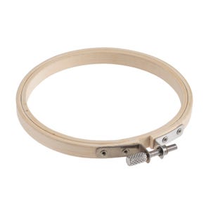 May include: A round, light-colored wooden embroidery hoop with a metal tightening mechanism. The hoop is made of two wooden rings held together by a metal screw and bracket. The wood has a natural grain.