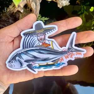 May include: A sticker featuring a cartoon illustration of a man wearing a sombrero holding a large fish. The text "Off the Grid John" is printed on the sticker.