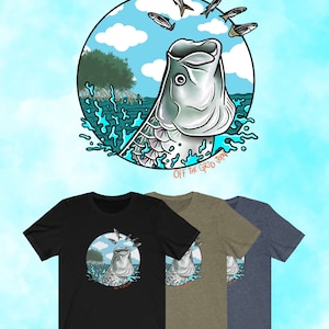 May include: A black, green, and blue t-shirt with a graphic of a fish jumping out of the water. The fish is surrounded by smaller fish and the text "Off the Grid" is below the fish.