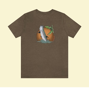 May include: A brown t-shirt with a graphic of a silver fish jumping out of the water with a green leaf and an orange sun behind it.