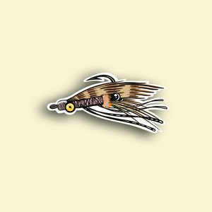 May include: A brown and tan fly fishing lure with a pink and black body and a yellow bead. The lure has a hook and feathers.