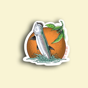 May include: A sticker featuring a cartoon illustration of a tarpon fish jumping out of the water in front of an orange circle with green leaves. The text "OFF THE GRID VIBES" is written on the sticker.