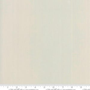 May include: Off-white fabric with subtle vertical lines. The fabric has a soft, muted color and a smooth texture. A ruler is at the bottom of the image, with measurements in inches.