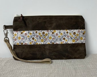 waxed canvas wristlet clutch, warm brown color with floral accent fabric on front and back,  zipper top and removable strap