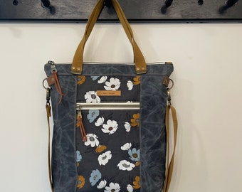 Waxed canvas tote in charcoal grey with coordinating floral cotton accent panels.  Hand straps plus removable shoulder/crossbody strap.