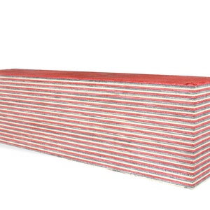 Può includere: Un blocco rettangolare di legno con strati alternati di legno rosso e bianco. Il blocco è lungo circa 30 cm e largo 10 cm.