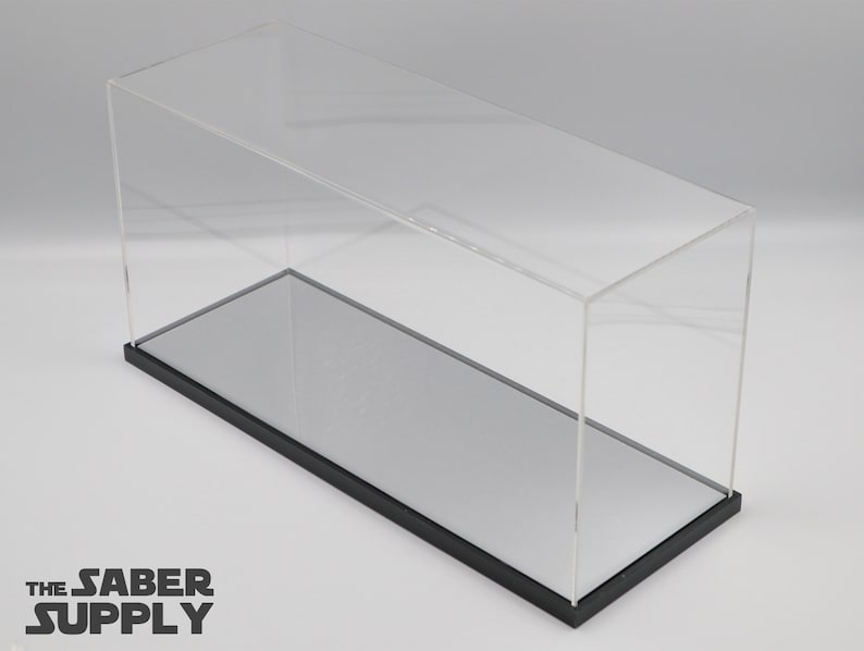 K&ouml;nnte beinhalten: Eine transparente Acryl-Vitrine mit schwarzem Sockel und einem verspiegelten Boden. Die Vitrine ist leer.