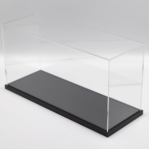 Puede incluir: Una vitrina de exhibici&oacute;n de acr&iacute;lico transparente con una base negra. La vitrina est&aacute; vac&iacute;a y tiene una forma rectangular.