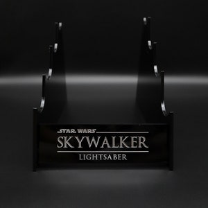 May include: Black plastic stand with five slots for displaying lightsabers. The stand has the text "STAR WARS SKYWALKER LIGHTSABER" printed on the front.
