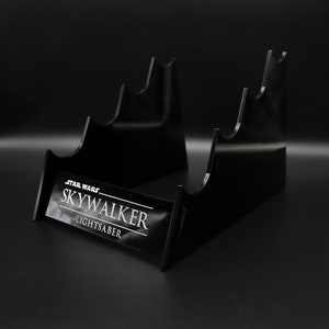 May include: Black acrylic lightsaber stand with the text "STAR WARS SKYWALKER LIGHTSABER" on the front.