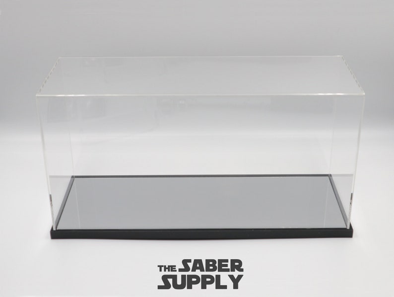 K&ouml;nnte beinhalten: Eine transparente Acryl-Vitrine mit schwarzem Sockel und einem grauen, verspiegelten Boden. Die Vitrine ist leer.