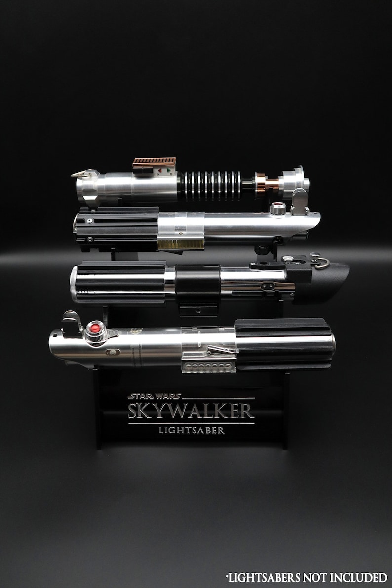 May include: A black stand with the text "STAR WARS SKYWALKER LIGHTSABER" displays four silver and black lightsaber replicas.