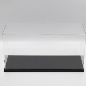 Puede incluir: Una vitrina de exhibici&oacute;n de acr&iacute;lico transparente con una base negra. La vitrina es rectangular y tiene una parte superior plana.