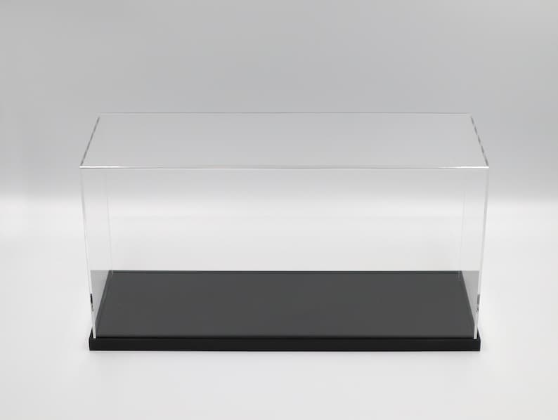 Puede incluir: Una vitrina de exhibici&oacute;n de acr&iacute;lico transparente con una base negra. La vitrina es rectangular y tiene una parte superior plana.