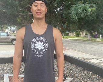 May include: A man wearing a black tank top with a white lotus flower graphic and the text "May you be peaceful, may you be free, may you be happy".