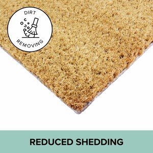May include: A rectangular doormat made of natural fibers, with a light brown color. A white circle with a black illustration of a broom sweeping dirt is in the upper left corner. The text "DIRT REMOVING" is around the circle. The words "REDUCED SHEDDING" are at the bottom.